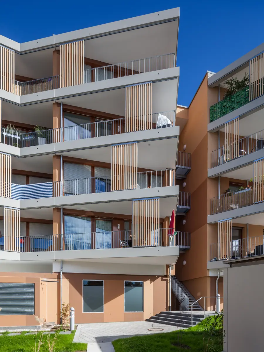 Edificio residenziale con balconi profondi, lamelle verticali e struttura di facciata chiaramente articolata.