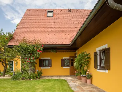 Gelbes Haus mit roten Dachziegeln, Blumenkästen, offenen Fensterläden und bepflanztem Vorgarten.