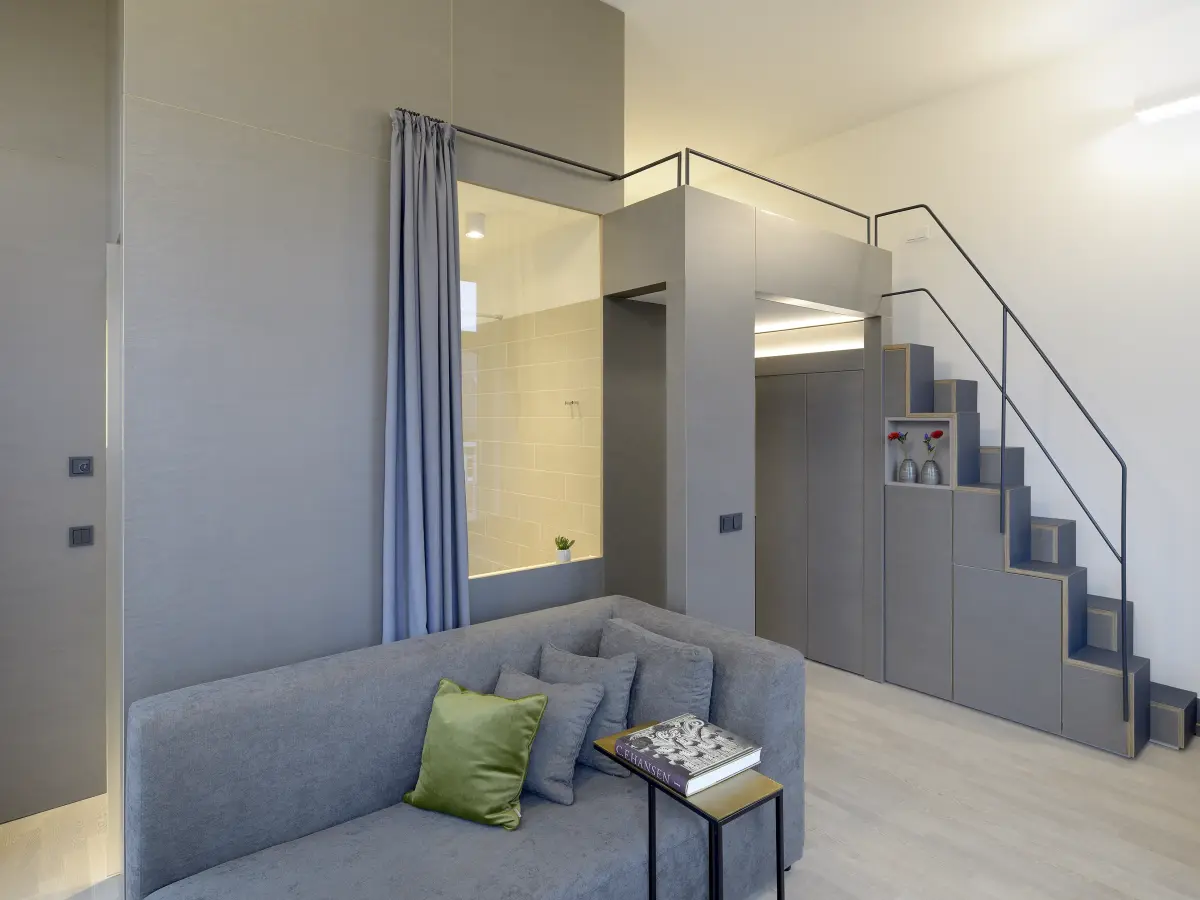 Blick in den Raum mit Sofa, Fenster zum Bad und Treppe zur Schlafebene