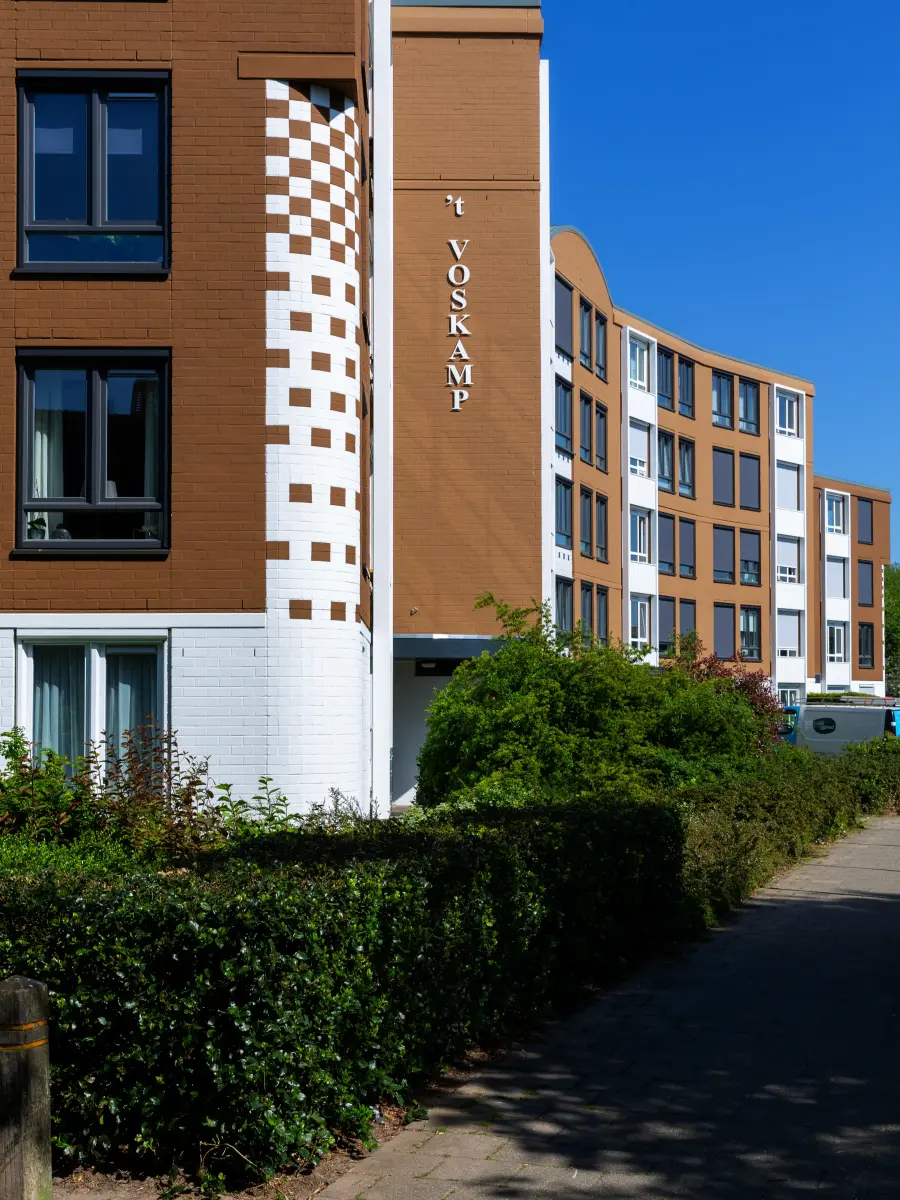 Braune Fassade eine Wohnkomplexes mit einer Hecke davor