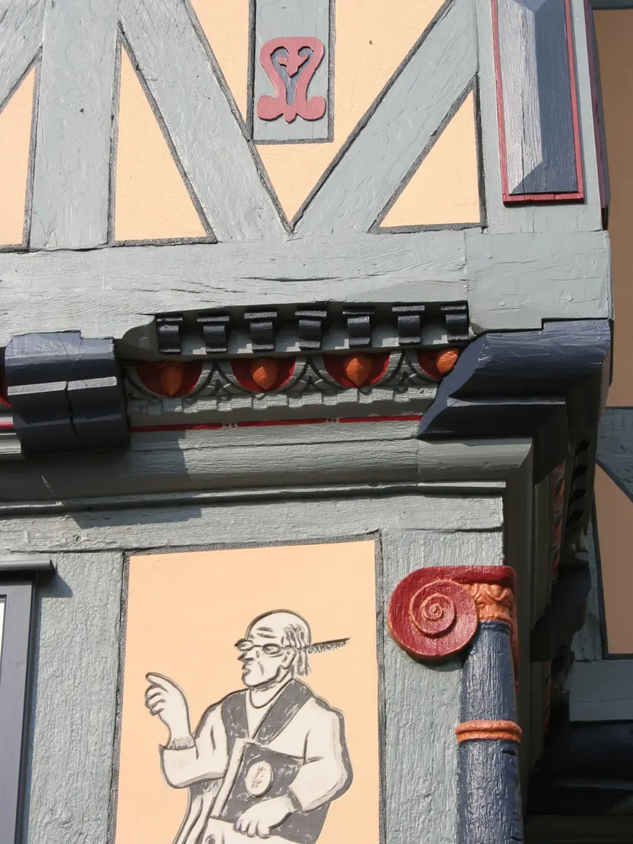 Detailaufnahme Eckschnitzerei in kräftigem Braunocker bis Orange, Dunkelrot und dunklem Blaugrau
