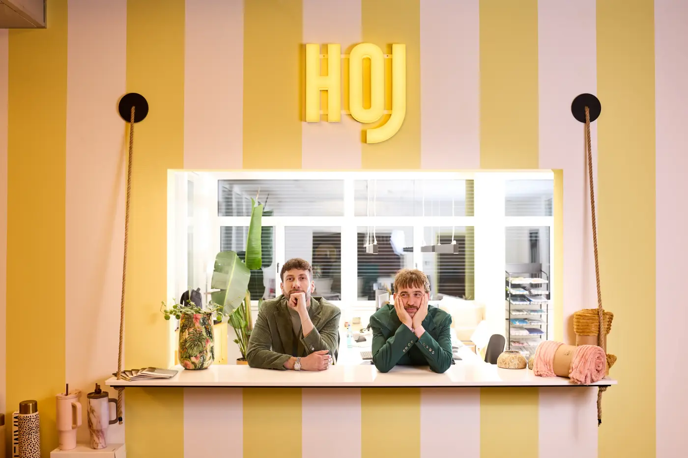 Michael und Christof lehnen an einem Thresen mit der Inschrift HOJ darüber