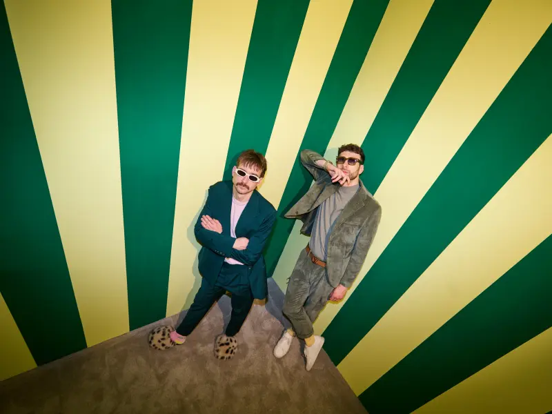 Christof und Michael lehnen an eine gestreifte Wand