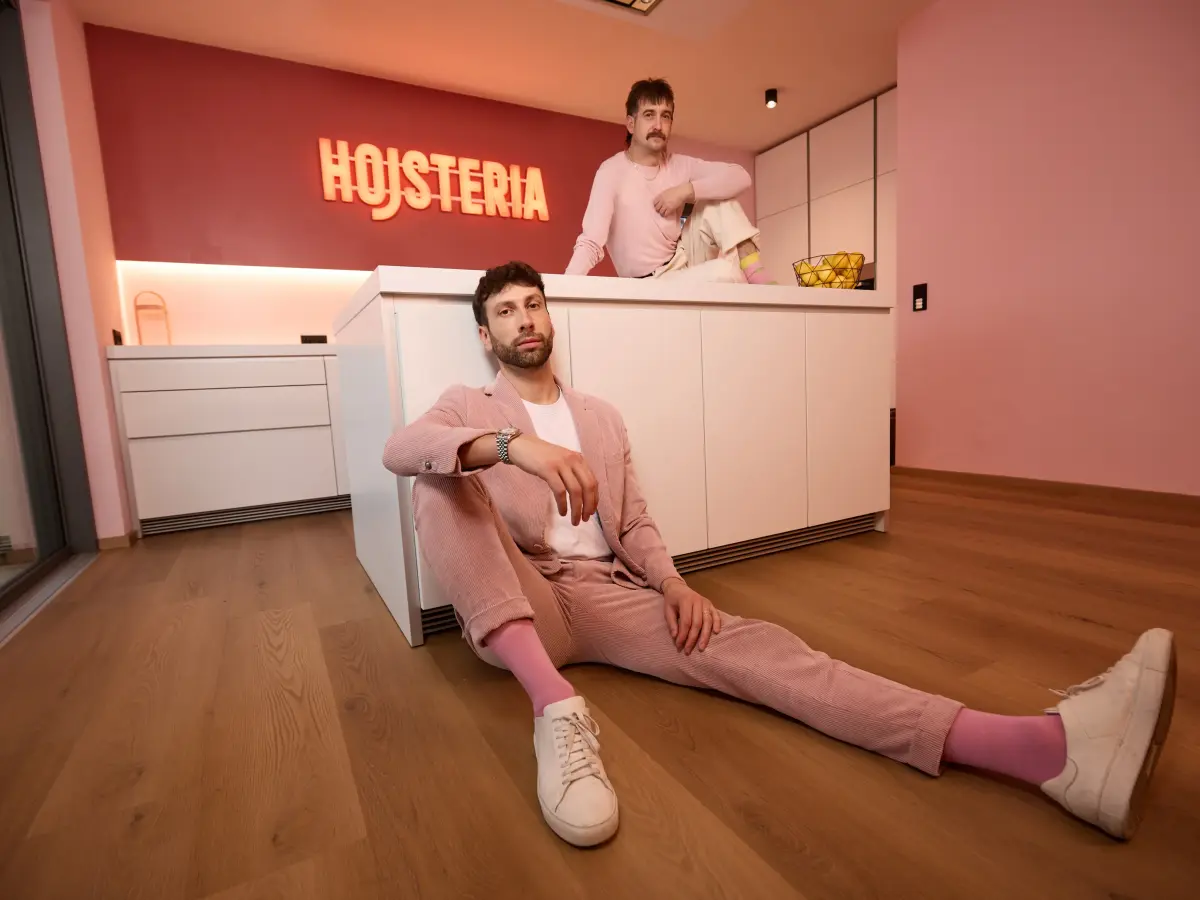 Michael und Christof sitzen in einer pinkfarbenen Küche auf dem Boden