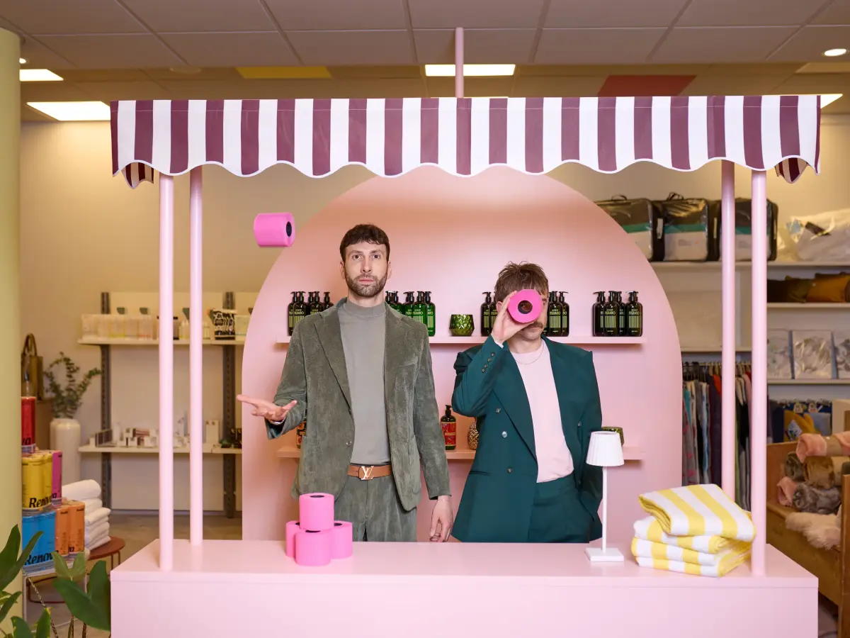 Christof und Michael stehen an einem pinkfarbenen Verkaufsstand