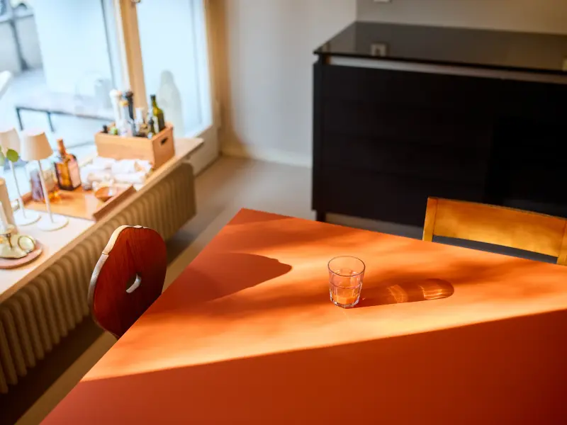 Auf einem orangefarbenen Tisch steht ein Glas Karottensaft.