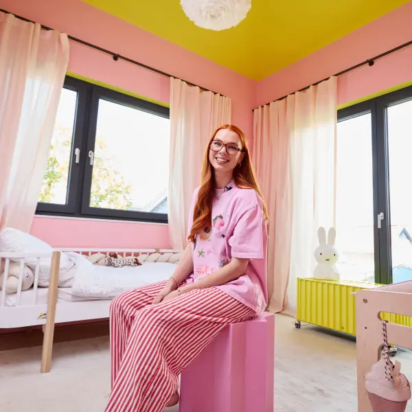 Jantien sitzt auf einem rosafarbenen Hocker im Kinderzimmer
