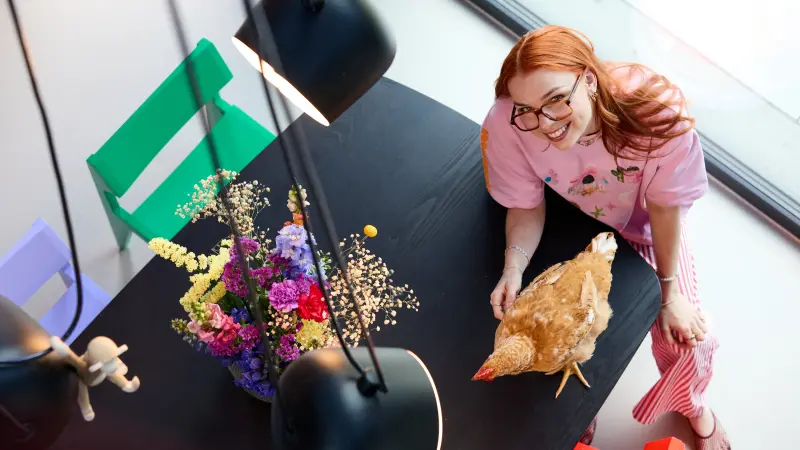 Jantien von das.bruns.haus mit einem Huhn auf dem schwarzen Küchentisch