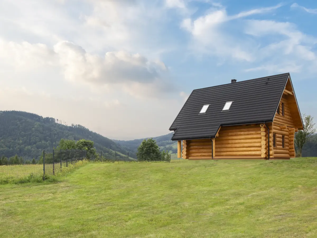 Holzerne Hütte auf einer hügeligen Wiese mit weiter freier Landschaft