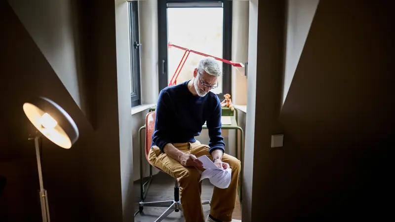 Mann sitzt auf Stuhl und liest