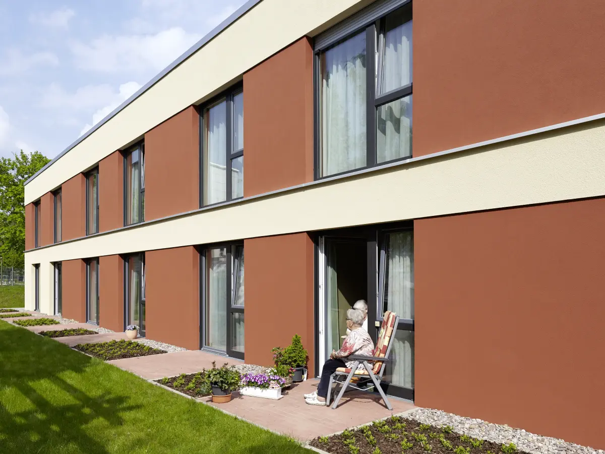 Rostton der Fensterspiegel harmoniert mit den roten Terrassensteinen