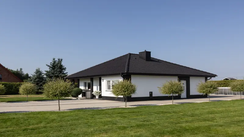 Bungalow mit weißer Fassade und schwarzem Dach
