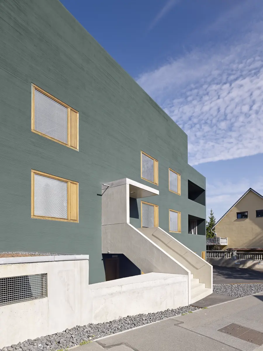 ein Gebäude mit einer grünen Fassade und gelben Fensterrahmen