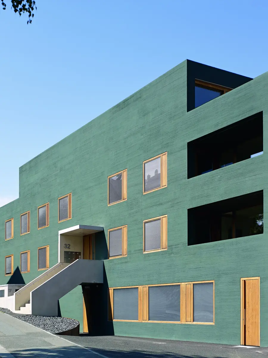 ein Gebäude mit einer grünen Fassade und gelben Fensterrahmen