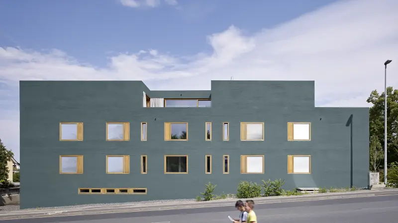 ein Gebäude mit einer grauen Fassade und gelben Fensterrahmen