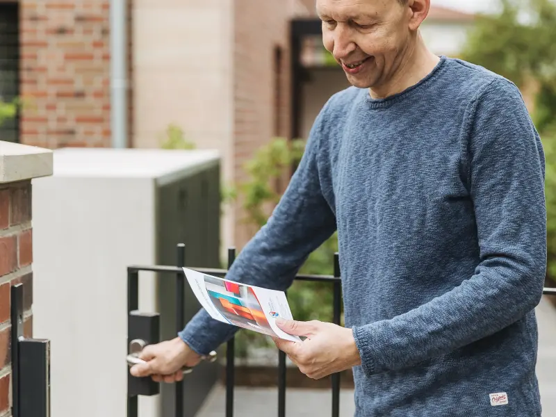 Mann hält Broschüre in der Hand an der Tür