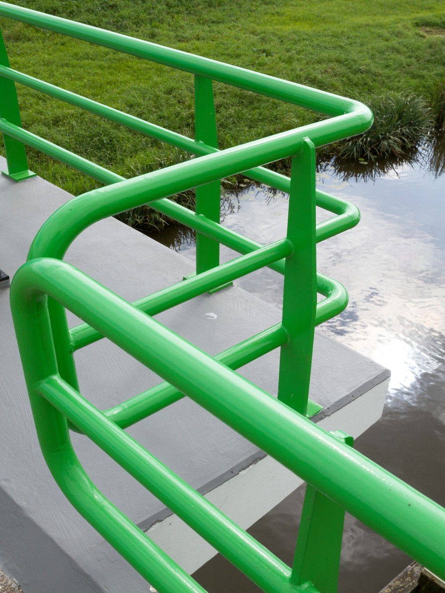 grünlackiertes Geländer über einem Fluss