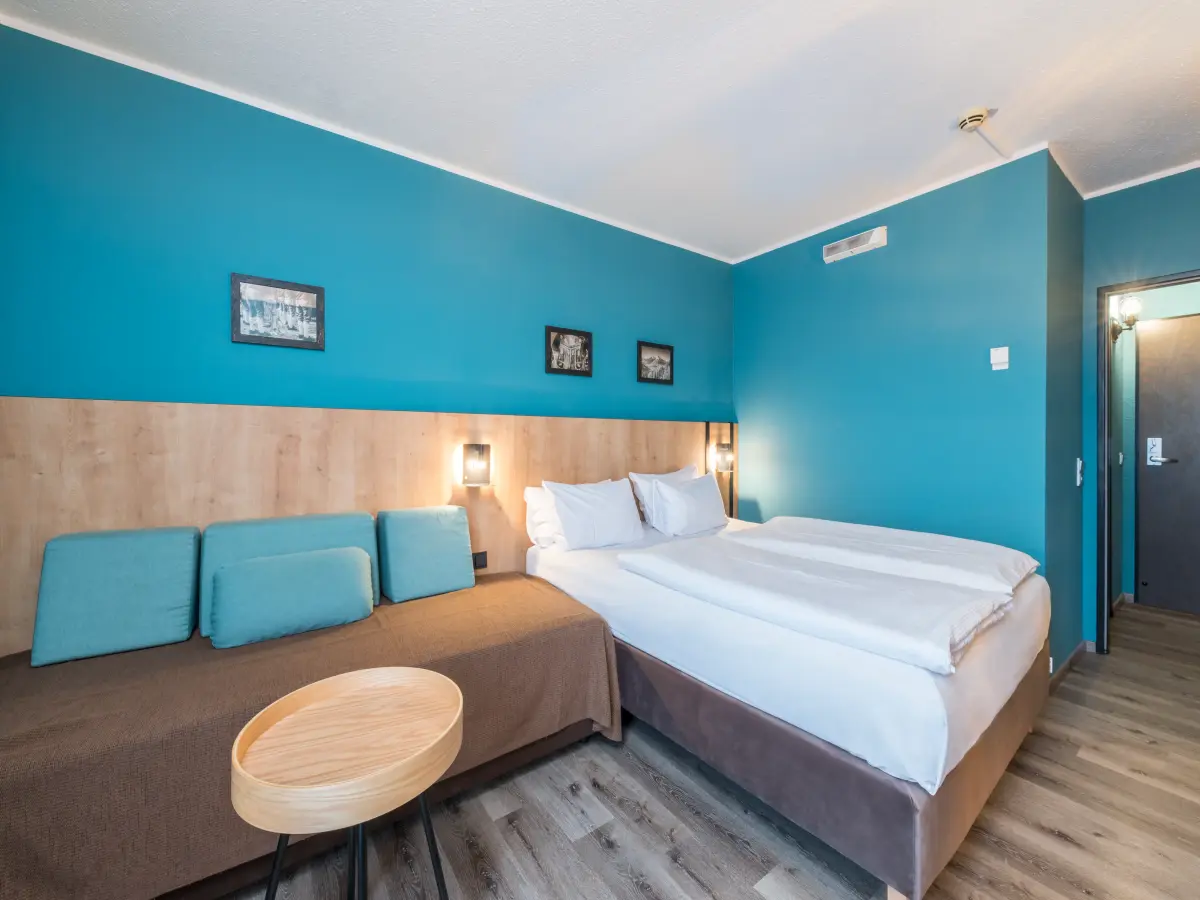 Ein Schlafzimmer eines Hotels mit türkiser Wandfarbe