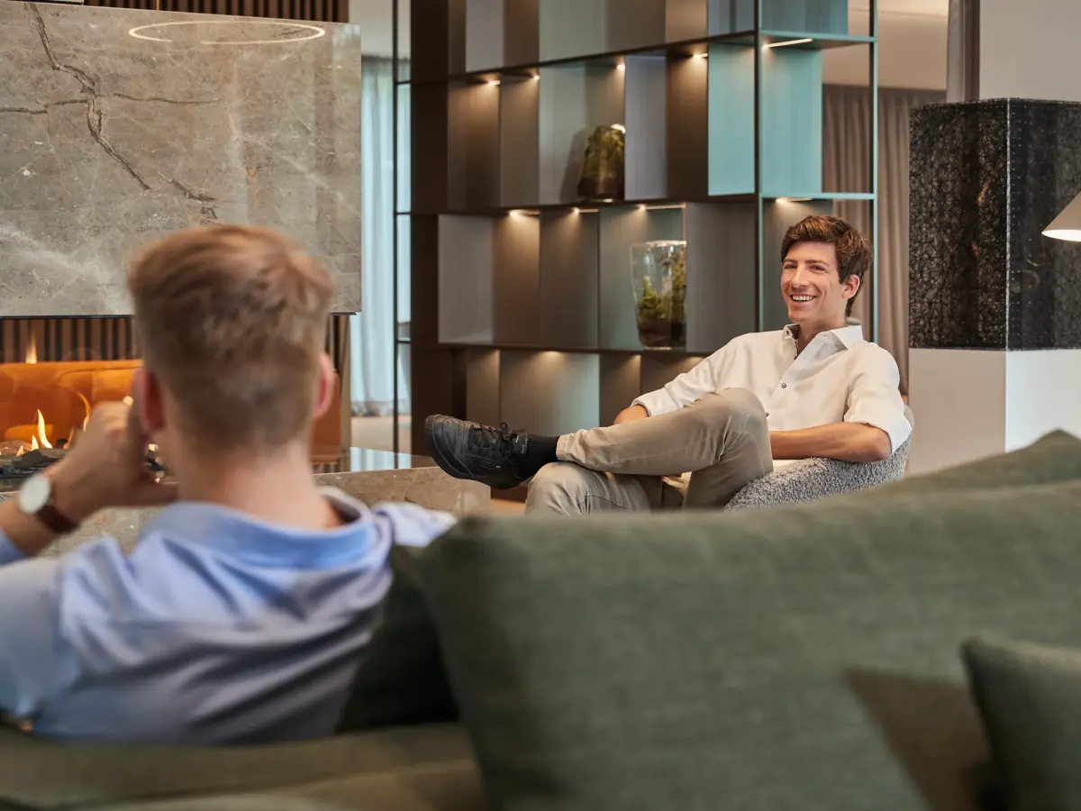 zwei Männer sitzen vor dem Kamin in einer Sofalounge