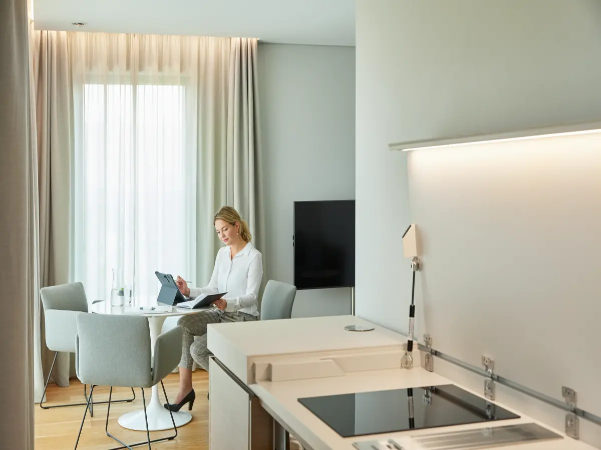 Eine Person sitzt im Hotelzimmer des B-Wohnen