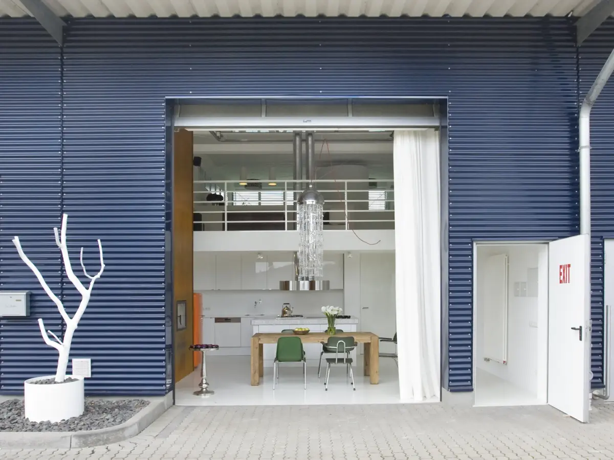 Aussenansicht: gewöhnlicher Gewerbebau - blaue Rillenoptik und Einblick in das ungewöhnliche Loft