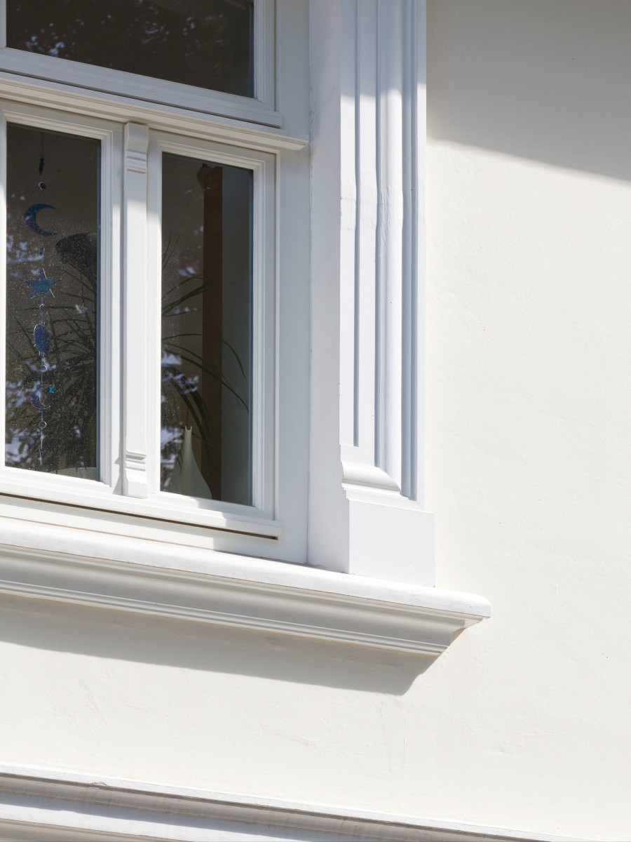 Detaillierte Nahaufnahme einer weißen Fensterumrandung im klassischen Stil, einschließlich des Sims und des Fensterrahmens.