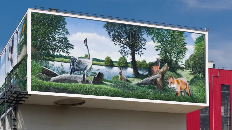 Betonkopf mit Gemälde von Wildtieren im Wald an einem See