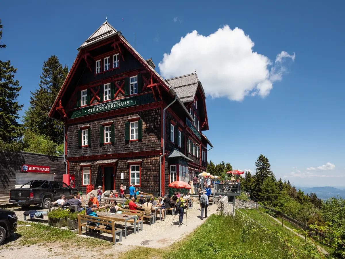 Das historische Stubenberghaus am Stöckl in St. Radegund, umgeben von grüner Landschaft, mit Gästen auf der Terrasse und malerischem Ausblick.