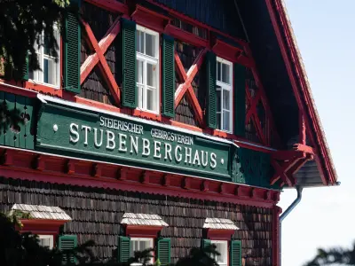 Fassade des Stubenberghauses des Steirischen Gebirgsvereins mit grün-roten Holzelementen und grünen Fensterläden.