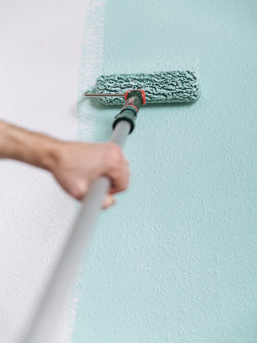 Frau streicht mit einer Rolle