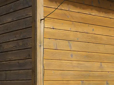 Holzwand mit hellen und dunklen Brettern, Kabel an der Ecke.