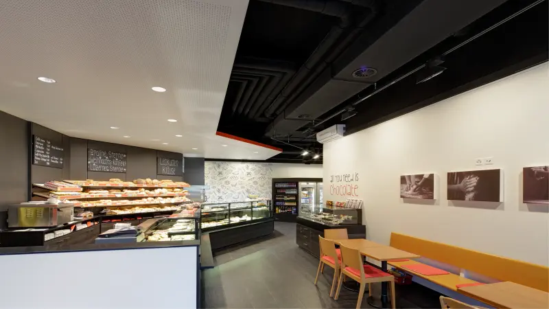 Moderne Bäckerei mit Auslagen, Sitzbereich und dekorierten Wänden.
