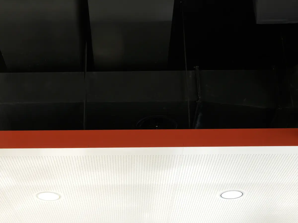 Detail der Decke mit abgesetztem roten Rahmen und integrierter Beleuchtung in der Bäckerei Brot & Co.