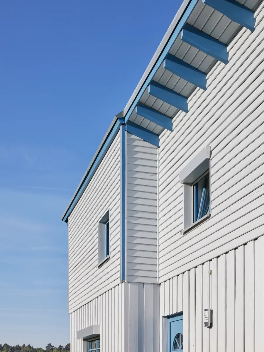 Weiße Holzfassade mit blauen Fenstern