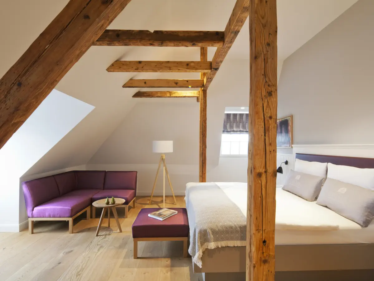 Schlafzimmer mit Doppelbett unterm Dach mit alten Holzbalken
