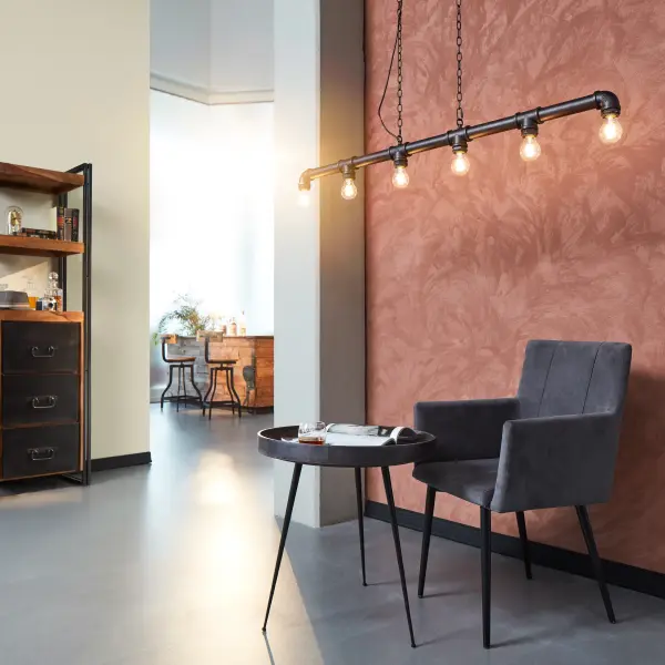 offener Raum mit einer besonders gestalteten Wand mit Tisch und Stuhl davor