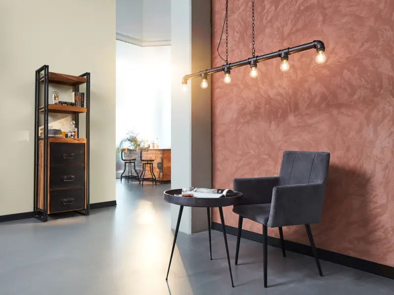 offener Raum mit einer besonders gestalteten Wand mit Tisch und Stuhl davor