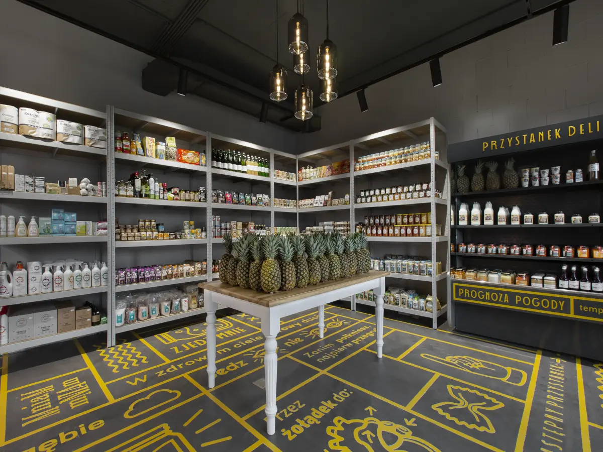 Holztisch mit Ananas und im Hintergrund Regale gefüllt mit Lebensmittel.