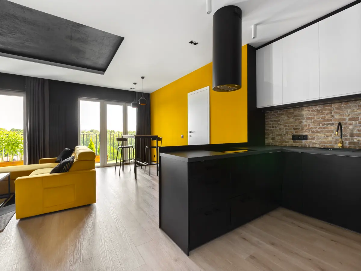 Schwarz weiße Küchenzeile mit der Hochtisch und gelber Wand im Hintergrund