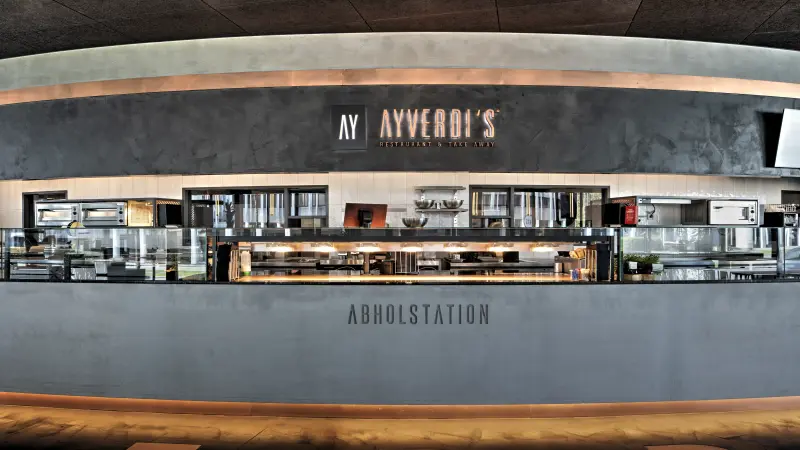 Moderne Abholstation in einem Restaurant mit Theke und Küchenbereich.