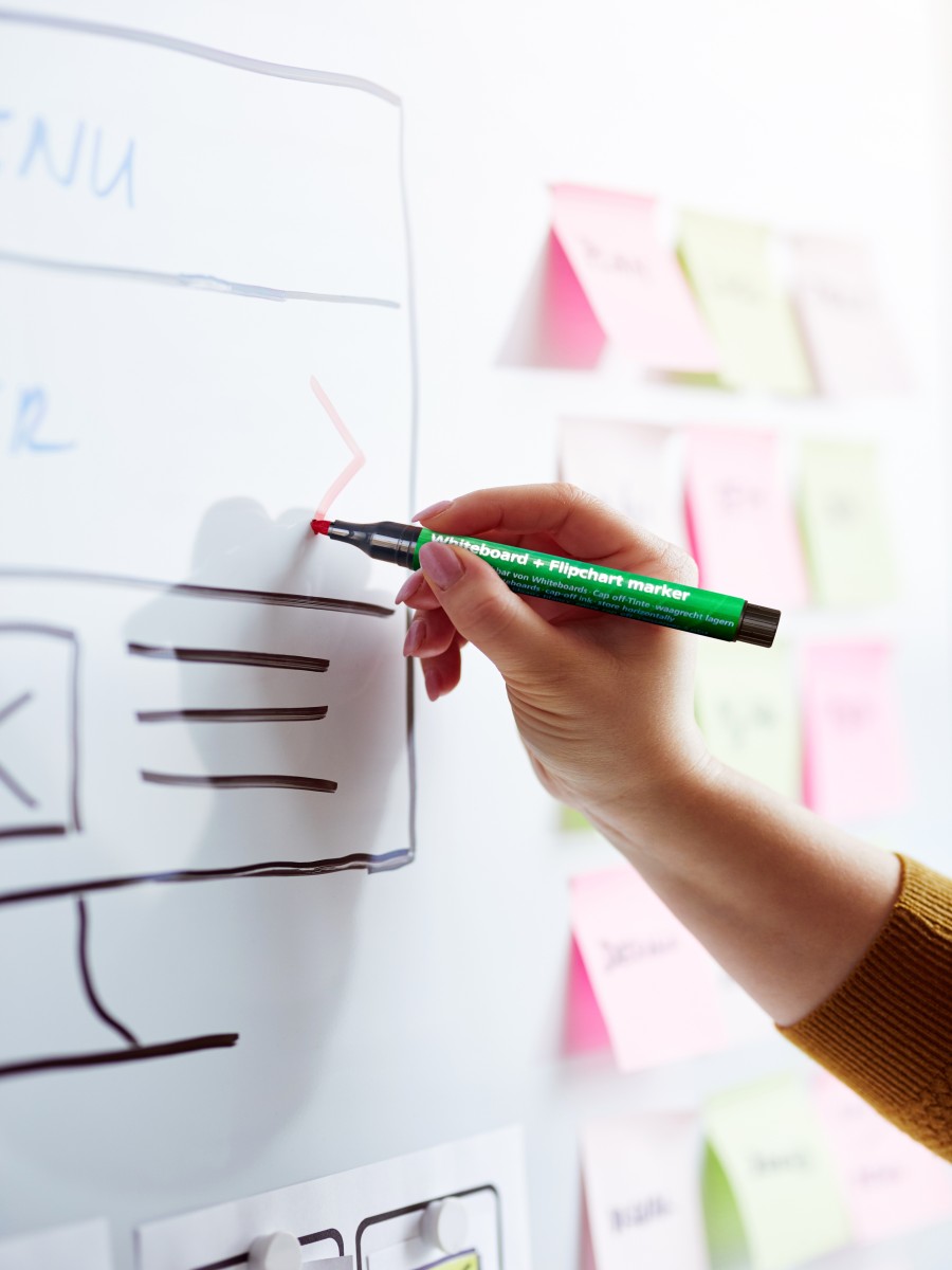 Person schreibt auf Whiteboard