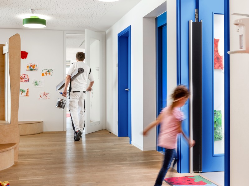 Mann mit Lacken verlässt den Eingangsbereich und geht in die Kita