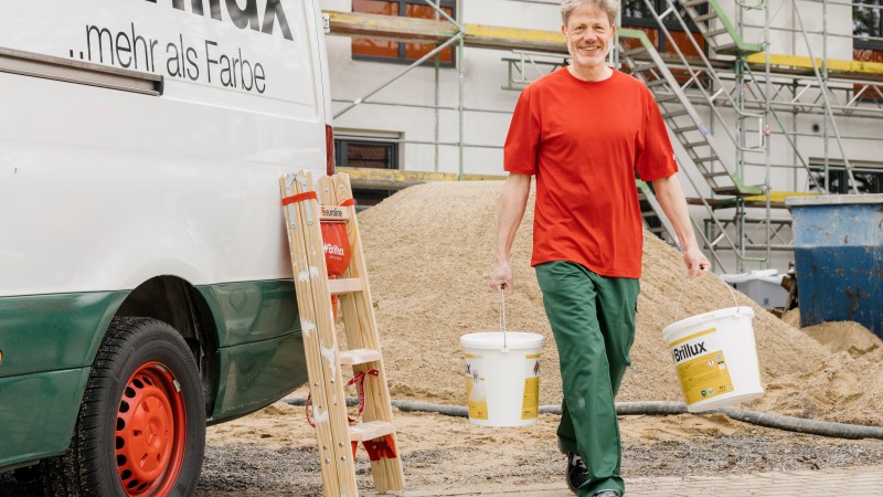Zwei Malerhandwerker und ein Berater gehen gemeinsam über eine Baustelle
