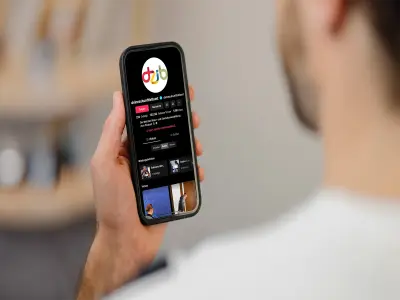 Hand hält Smartphone mit Instagram-Profil "deinezukunftistbunt". Unscharfer Hintergrund mit Person.