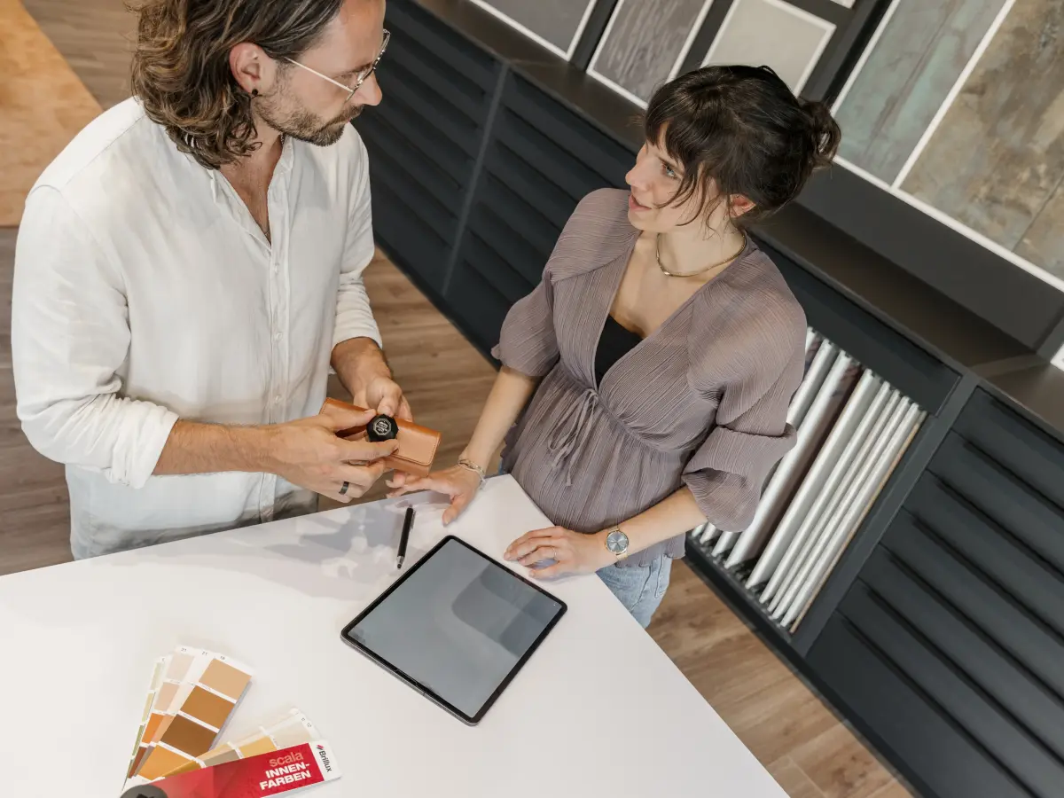 Ein Mann und eine Frau beraten sich an einem Tisch mit Tablet