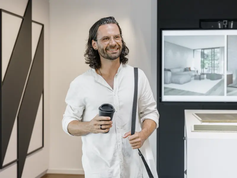 Mann steht lächelnd in einem Büro