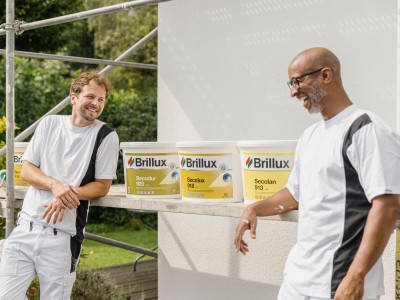 Zwei Personen stehen vor Secolux-Eimern und lachen