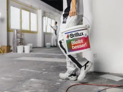 Ein Maler trägt einen Eimer Innendispersion
