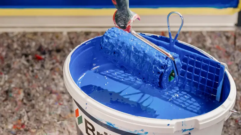 Ein Farbeimer mit blauer Farbe und Farbrolle