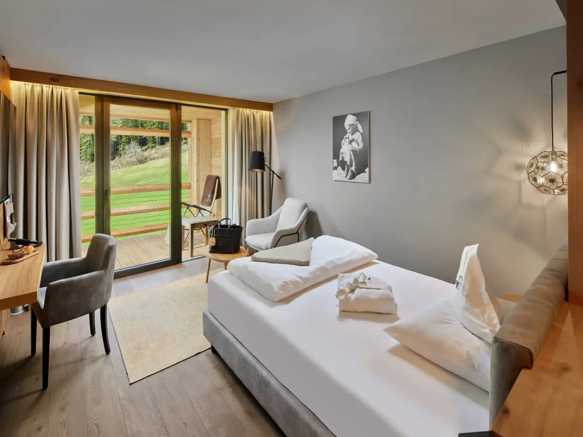 Camera d’albergo in effetto legno con letto bianco.